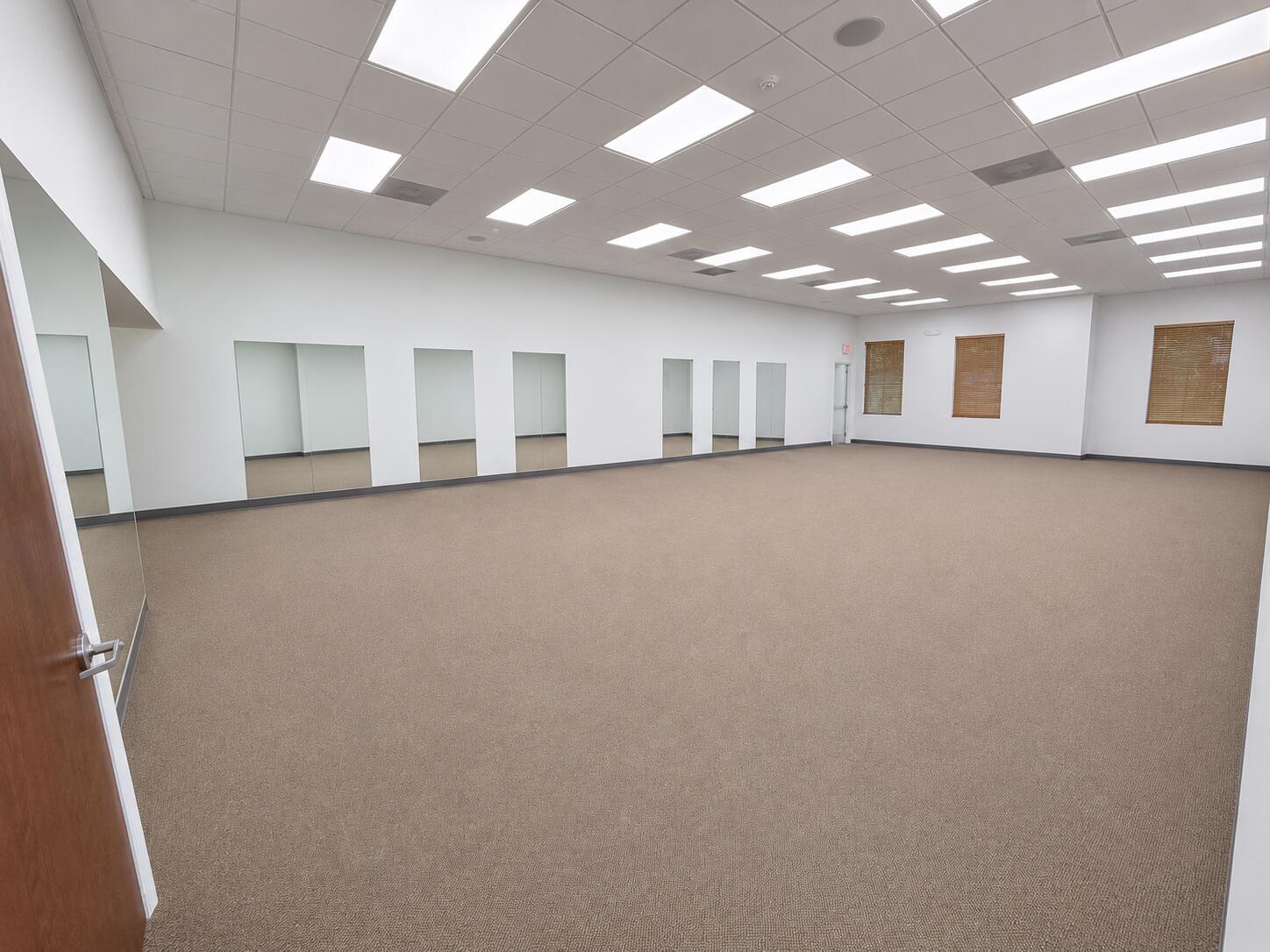 An empty room with beige carpet, white walls, mirrored panels, and a drop ceiling — 5055 S Congress Avenue # 301, Atlantis FL 33461, ATLANTIS, FL