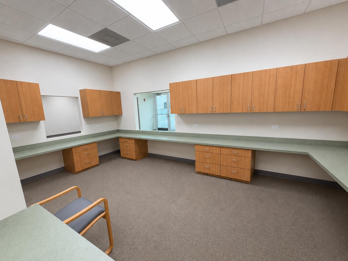 An office room features light wood cabinetry, green countertops, and gray carpeted flooring — 5055 S Congress Avenue # 301, Atlantis FL 33461, ATLANTIS, FL