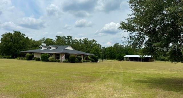 A single-story house with a metal roof sits on a large, grassy rural lot — 26645 COUNTY ROAD 33, GROVELAND, FL