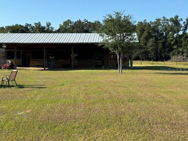 A wooden barn with a metal roof sits in a large, grassy field — 26645 COUNTY ROAD 33, GROVELAND, FL