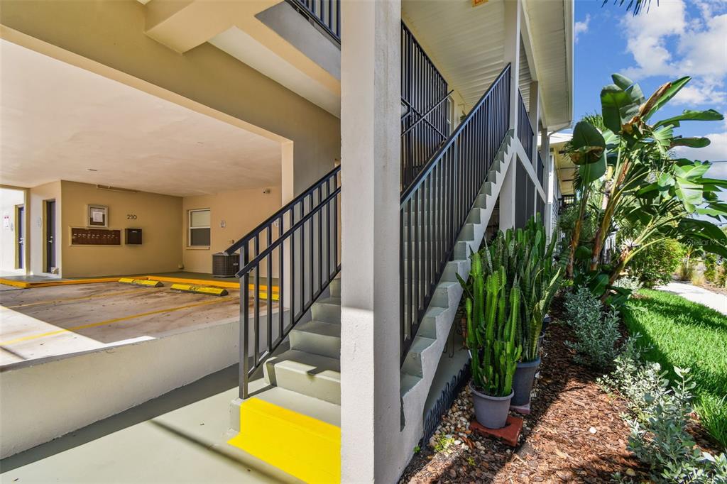 An outdoor staircase with black railings leads to an elevated covered parking area — 210 6TH AVENUE N UNIT 9, ST PETERSBURG, FL