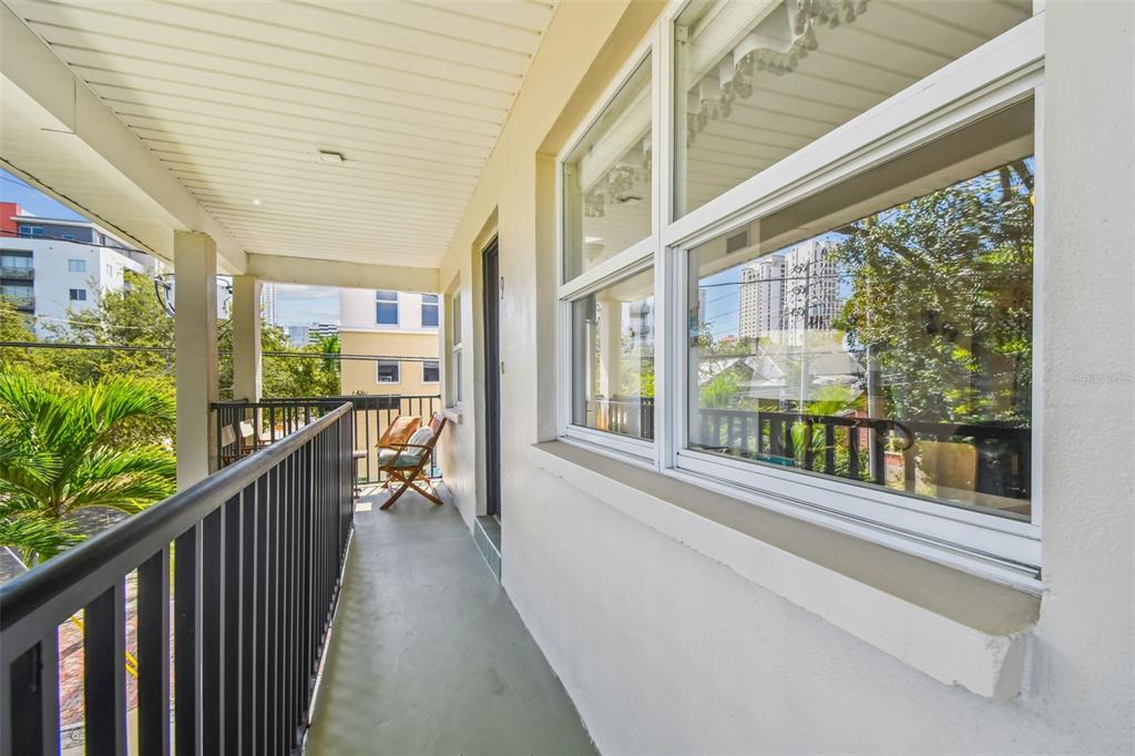 A covered outdoor balcony features a black metal railing, a beige wall, and large windows — 210 6TH AVENUE N UNIT 9, ST PETERSBURG, FL