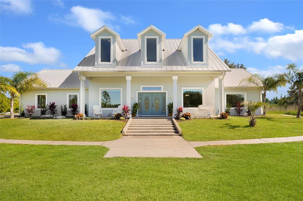 A light-colored house with a metal roof, three dormer windows, and a central front entrance — 11160 N US HIGHWAY 1, PALM COAST, FL