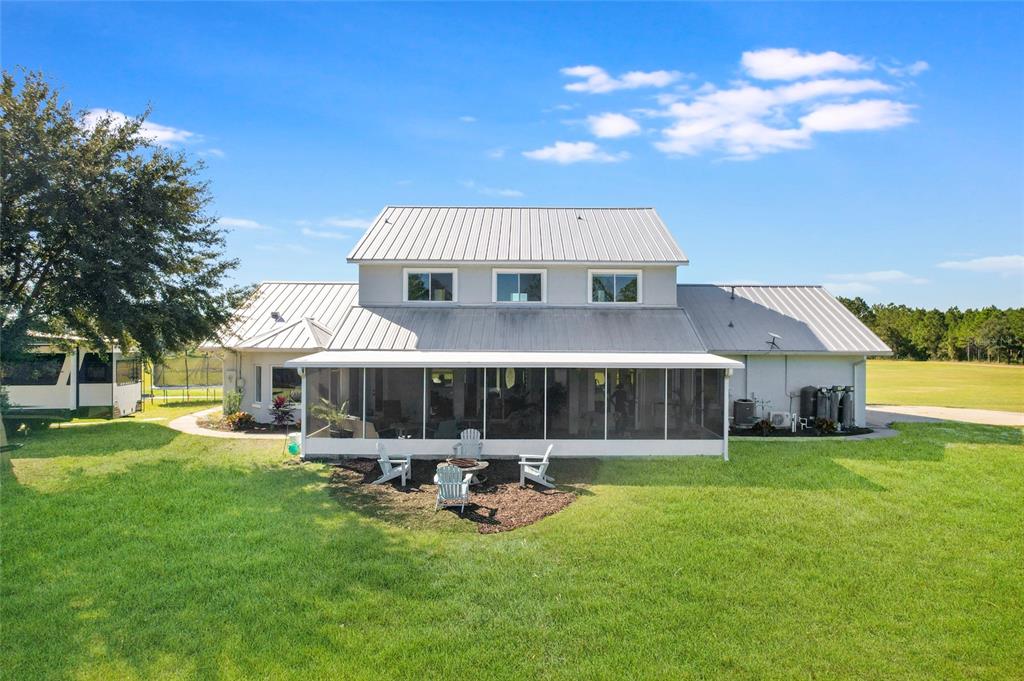 A two-story house with a metal roof and a screened-in back porch faces a lawn — 11160 N US HIGHWAY 1, PALM COAST, FL