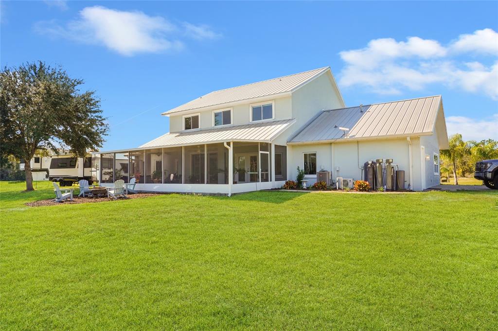 A two-story house with a metal roof and a large screened-in porch sits on grass — 11160 N US HIGHWAY 1, PALM COAST, FL