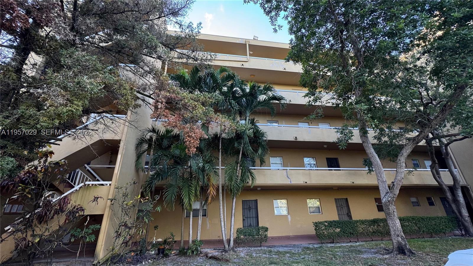 An exterior view of a multi-story apartment building with balconies and palm trees — 4111 Stirling Rd # 102, Dania Beach FL 33314, DANIA BEACH, FL