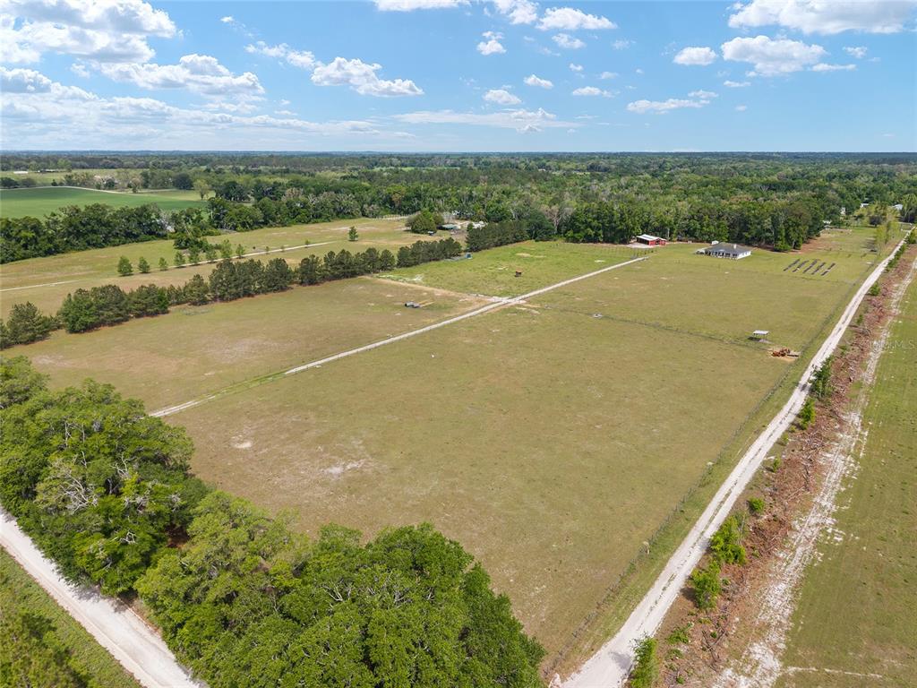 A covered concrete breezeway sits between a red metal building and an open-sided storage area — 3725 172ND STREET, WELLBORN, FL