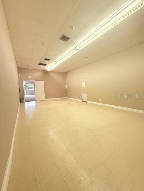 An empty commercial room features beige tiled floors, neutral walls, and a drop ceiling — 54 E MAIN STREET, APOPKA, FL