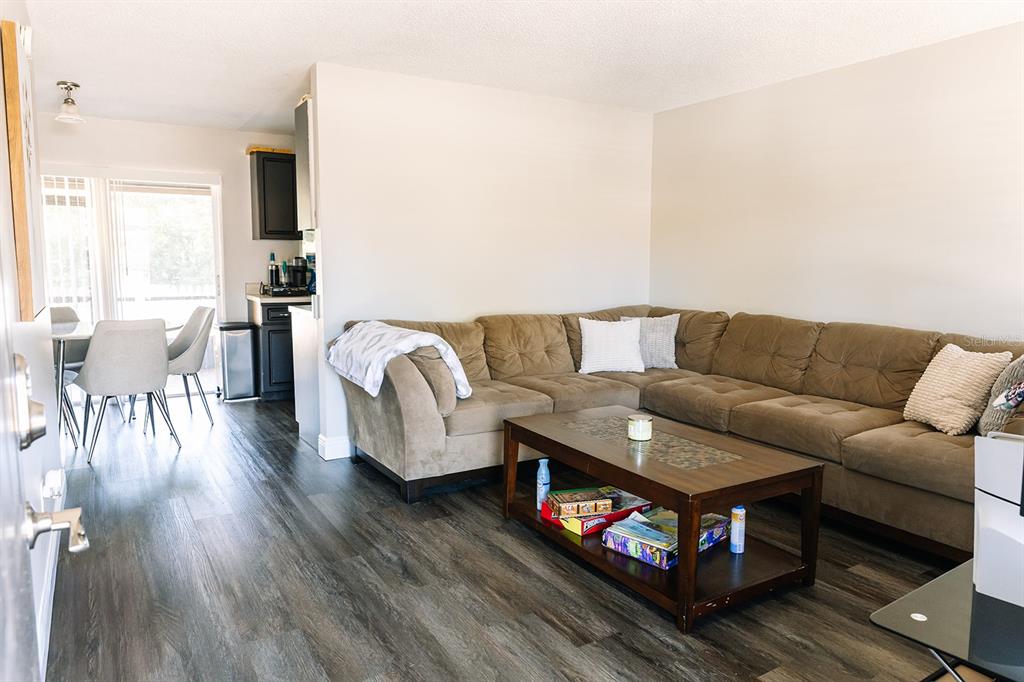 A living room with a brown sectional sofa, coffee table, and adjacent dining area — 14115 VILLAGE VIEW DRIVE, TAMPA, FL