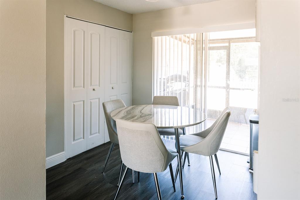 A dining area features a round marble-topped table, four upholstered chairs, and sliding glass doors — 14115 VILLAGE VIEW DRIVE, TAMPA, FL