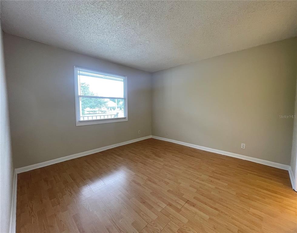 An empty bedroom features light-colored walls, wood-look flooring, and a single window — 5101 CURRY FORD ROAD UNIT 4, ORLANDO, FL