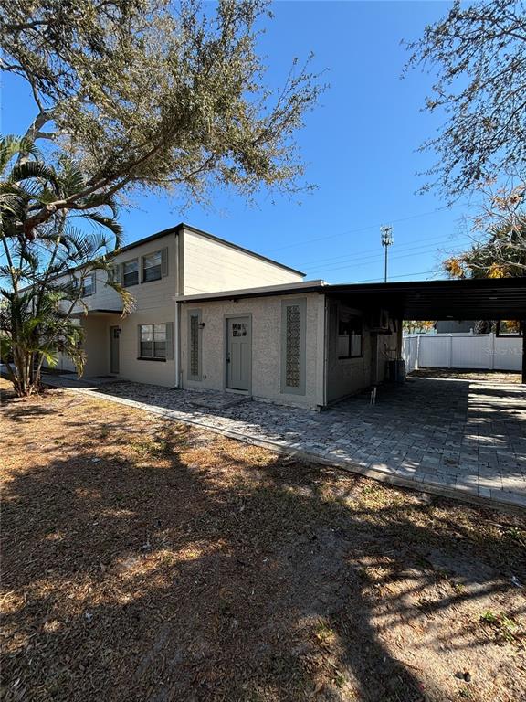 A two-story building with a paved driveway, a carport, and a light-colored stucco exterior — 11916 133RD AVENUE, LARGO, FL