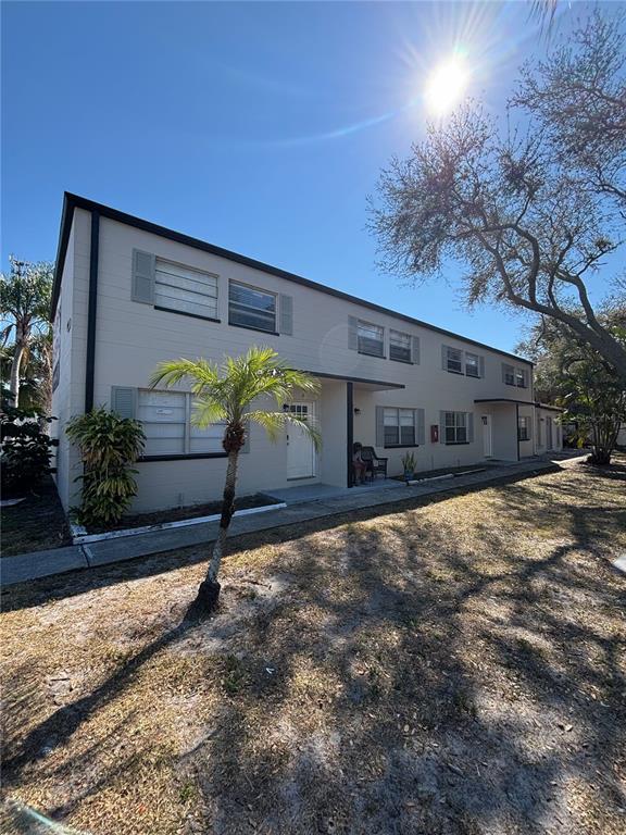 A two-story apartment building with light-colored siding, shutters, and a small palm tree — 11916 133RD AVENUE, LARGO, FL