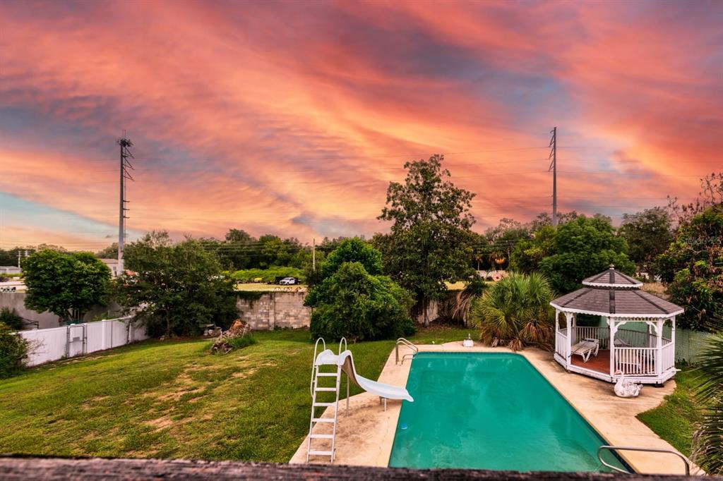 An outdoor backyard features a swimming pool with a slide and a white wooden gazebo — 1116 W LINE STREET, LEESBURG, FL