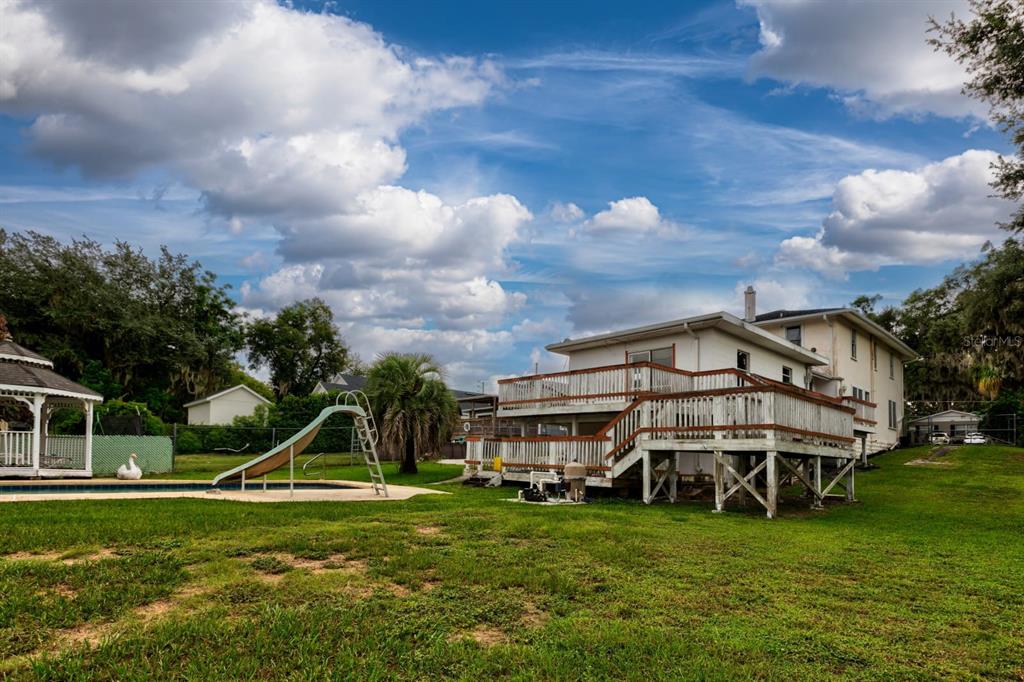A backyard view of a two-story house with a large wooden deck and swimming pool — 1116 W LINE STREET, LEESBURG, FL