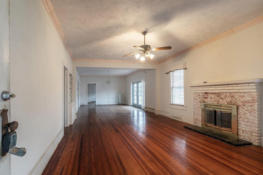 A living room with hardwood floors, a brick fireplace, and a ceiling fan — 1116 W LINE STREET, LEESBURG, FL