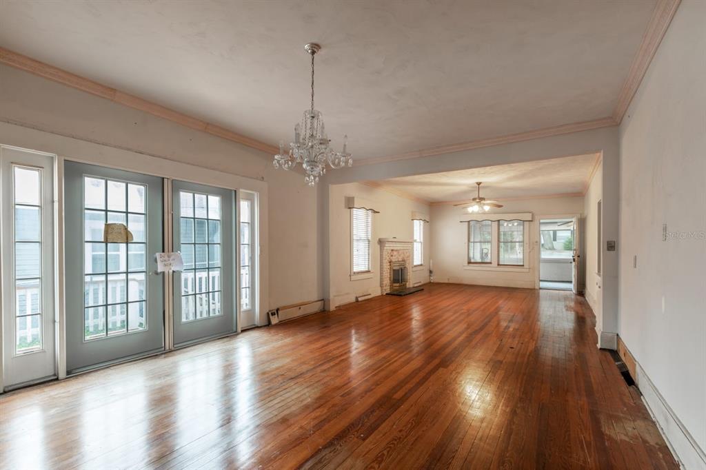 A spacious living room features hardwood floors, a crystal chandelier, and a brick fireplace — 1116 W LINE STREET, LEESBURG, FL