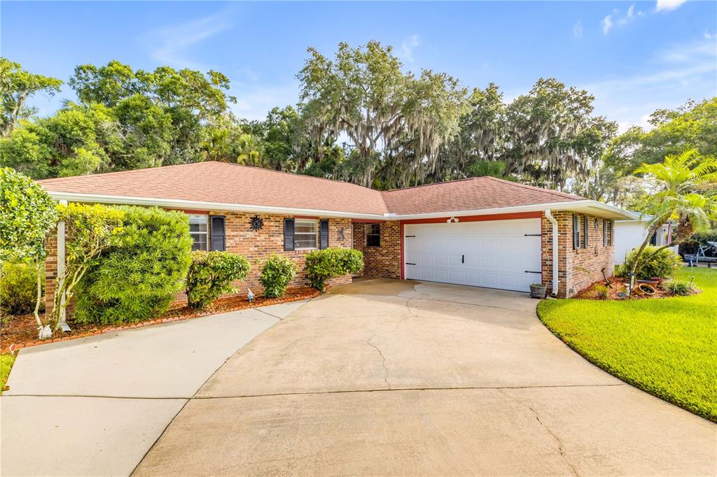 A brick ranch-style house features a two-car garage and a concrete driveway — 725 GREEN ROAD, NEW SMYRNA BEACH, FL