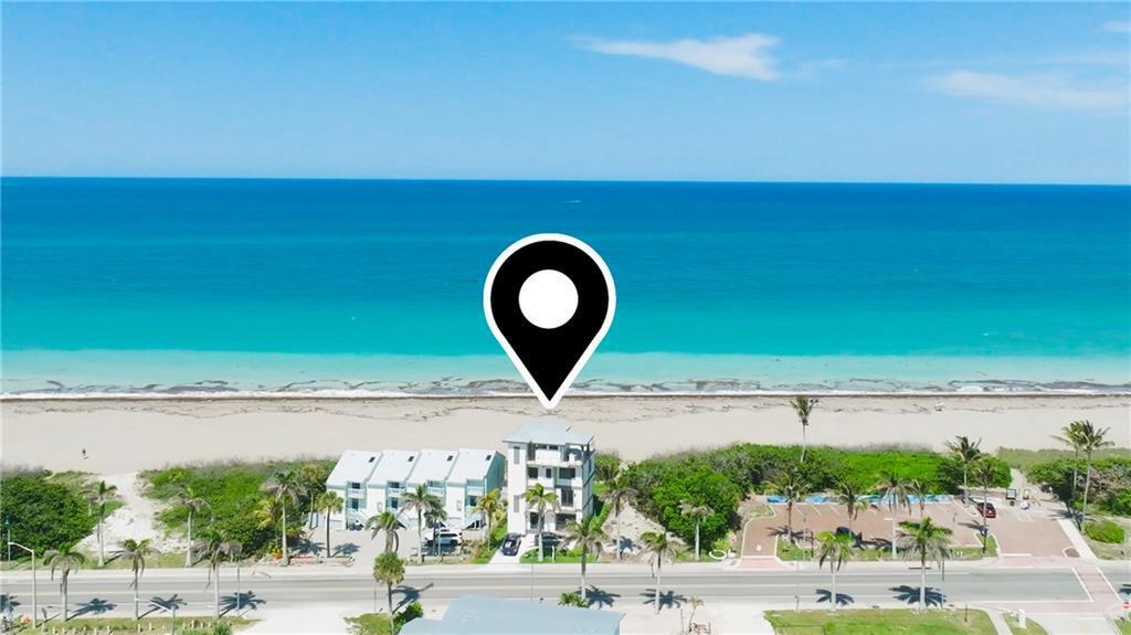 An aerial view shows a multi-story building situated directly on a sandy beach — HUTCHINSON ISLAND, FL