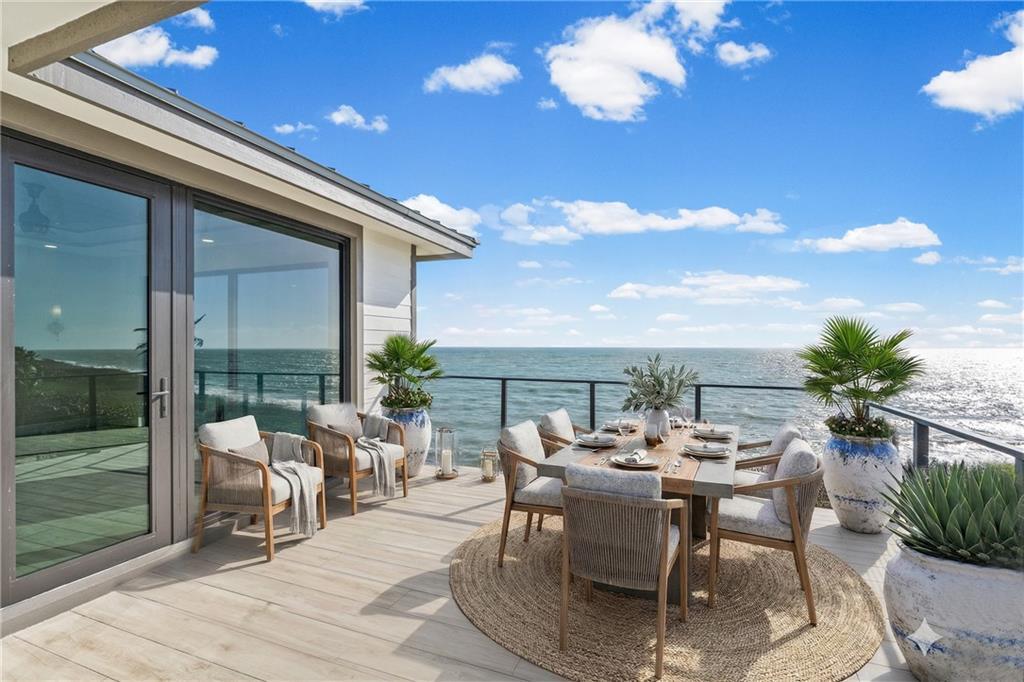 A wooden deck features a dining set and lounge chairs overlooking the ocean — HUTCHINSON ISLAND, FL