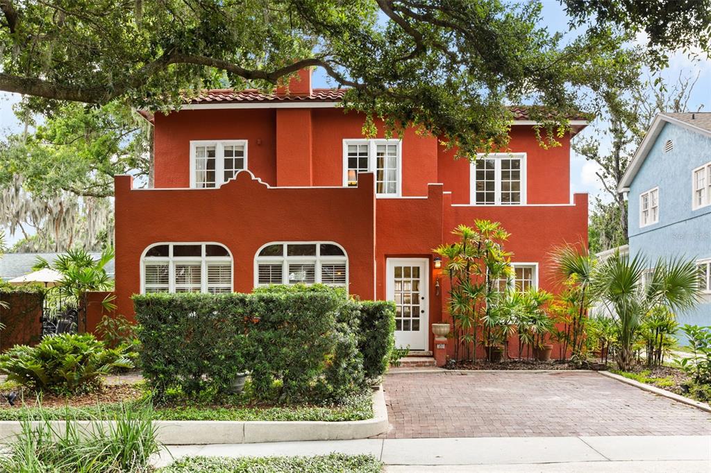 A two-story red stucco house features a brick driveway, arched windows, and lush landscaping — 318 VITORIA AVENUE, WINTER PARK, FL