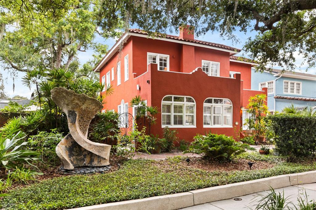 A two-story red stucco house features arched windows, a tile roof, and a large stone sculpture — 318 VITORIA AVENUE, WINTER PARK, FL