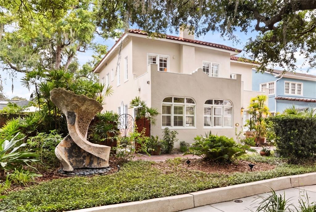 A two-story stucco house with a red tile roof and a large abstract stone sculpture — 318 VITORIA AVENUE, WINTER PARK, FL