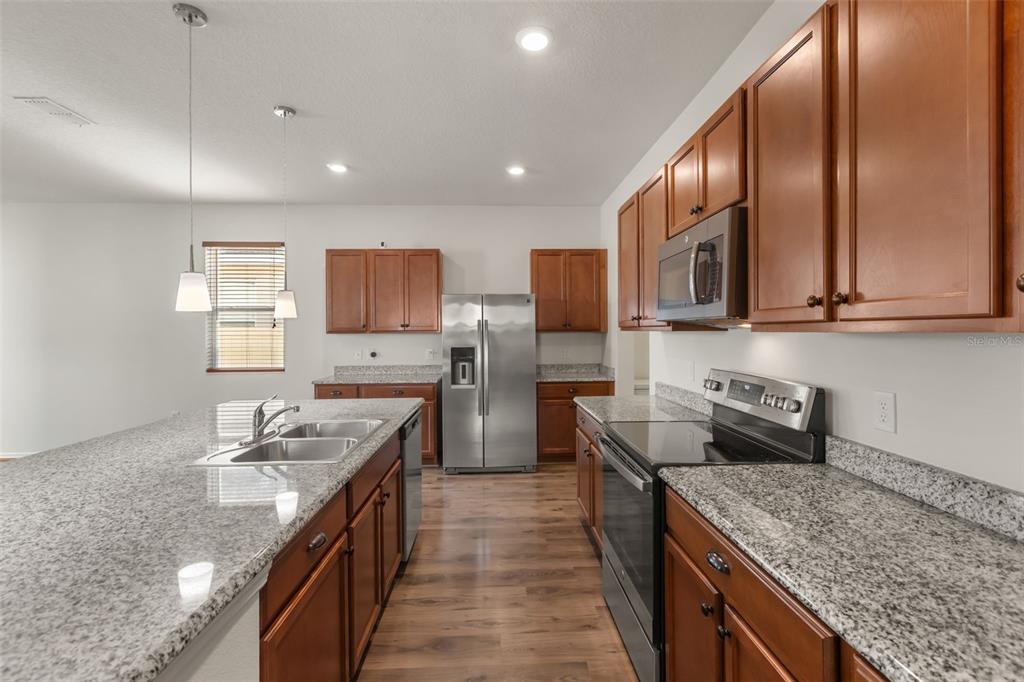 A kitchen with wood cabinets, granite countertops, stainless steel appliances, and a large center island — 12025 SUMTER DRIVE, ORLANDO, FL