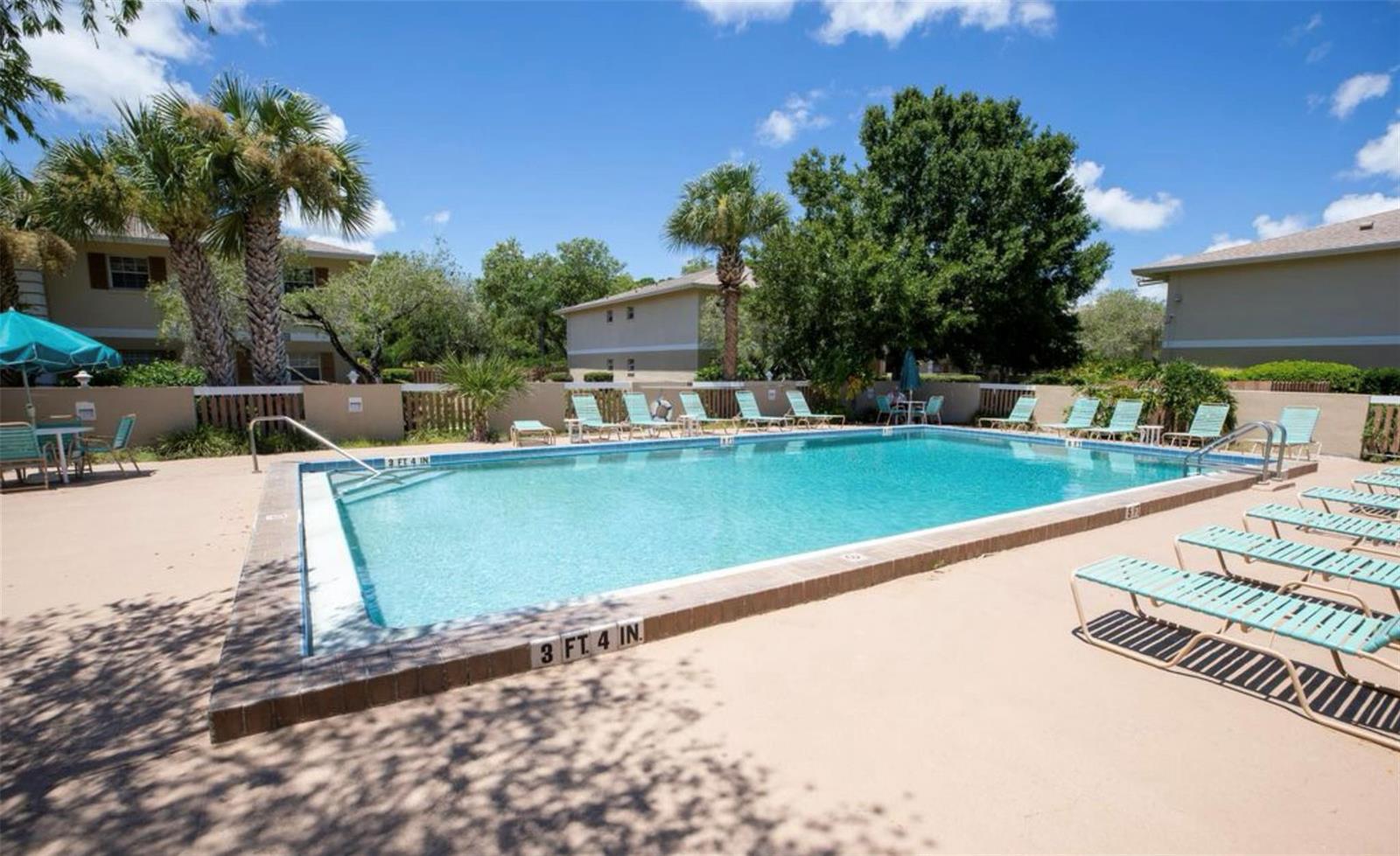 An outdoor swimming pool surrounded by lounge chairs, palm trees, and apartment buildings — 1640 NE Sunny Brook Lane # a203, Palm Bay FL 32905, PALM BAY, FL