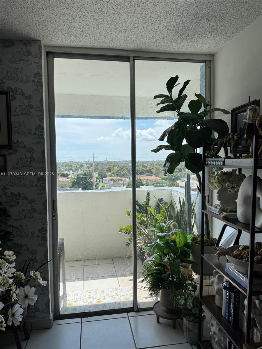 A sliding glass door opens to a balcony overlooking a suburban landscape with greenery — 5050 NW 7th St # 604, Miami FL 33126, MIAMI, FL