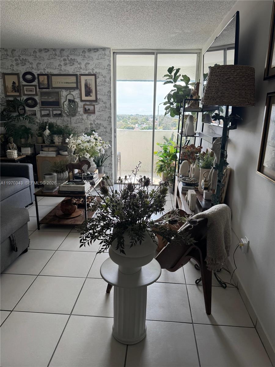 A living room features tiled floors, patterned wallpaper, a balcony, and various decorative plants — 5050 NW 7th St # 604, Miami FL 33126, MIAMI, FL
