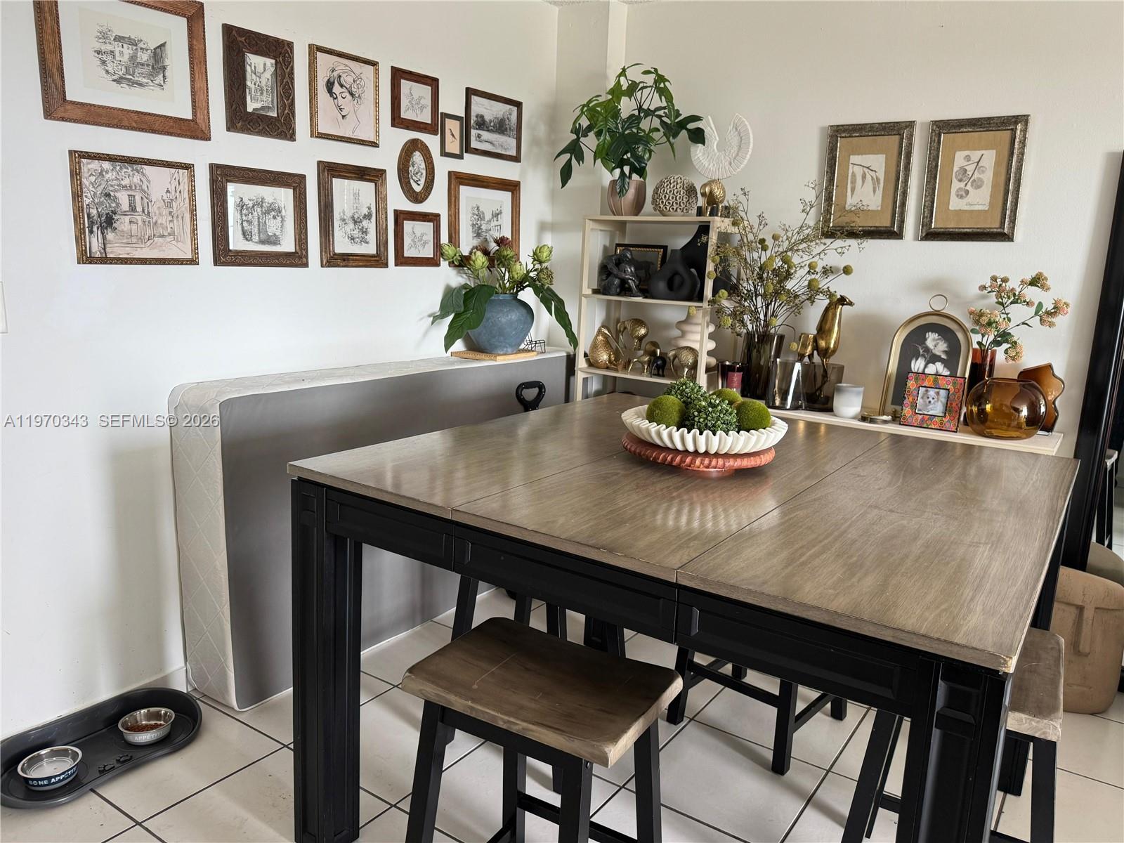 A dining room features a wooden table, stools, a gallery wall, and a mattress leaning against a wall — 5050 NW 7th St # 604, Miami FL 33126, MIAMI, FL