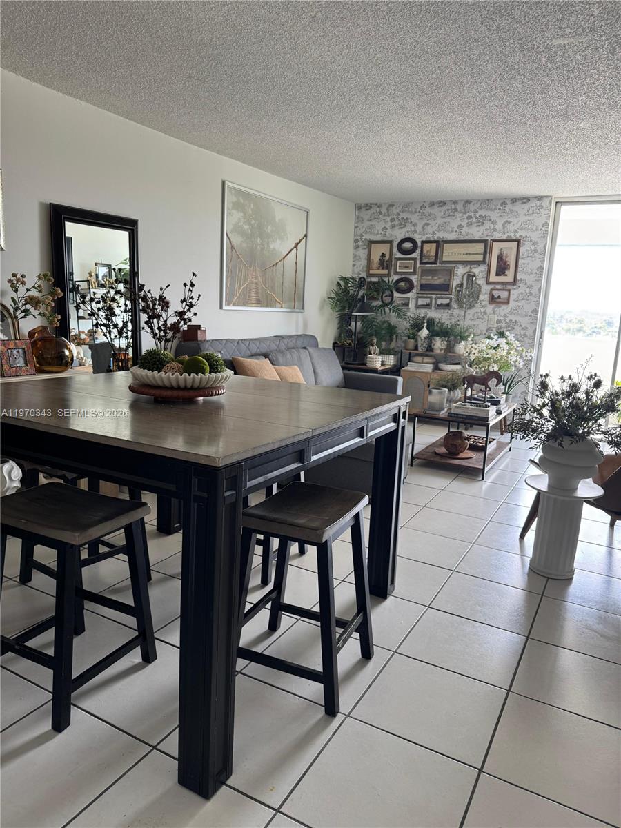 A dining area with a wooden table and stools sits before a living room space — 5050 NW 7th St # 604, Miami FL 33126, MIAMI, FL