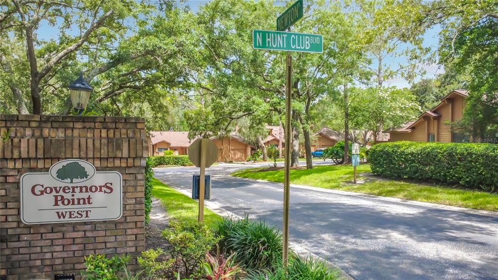 A brick entrance sign for Governors Point West stands at a street intersection with trees — 456 NEWTON PLACE, LONGWOOD, FL