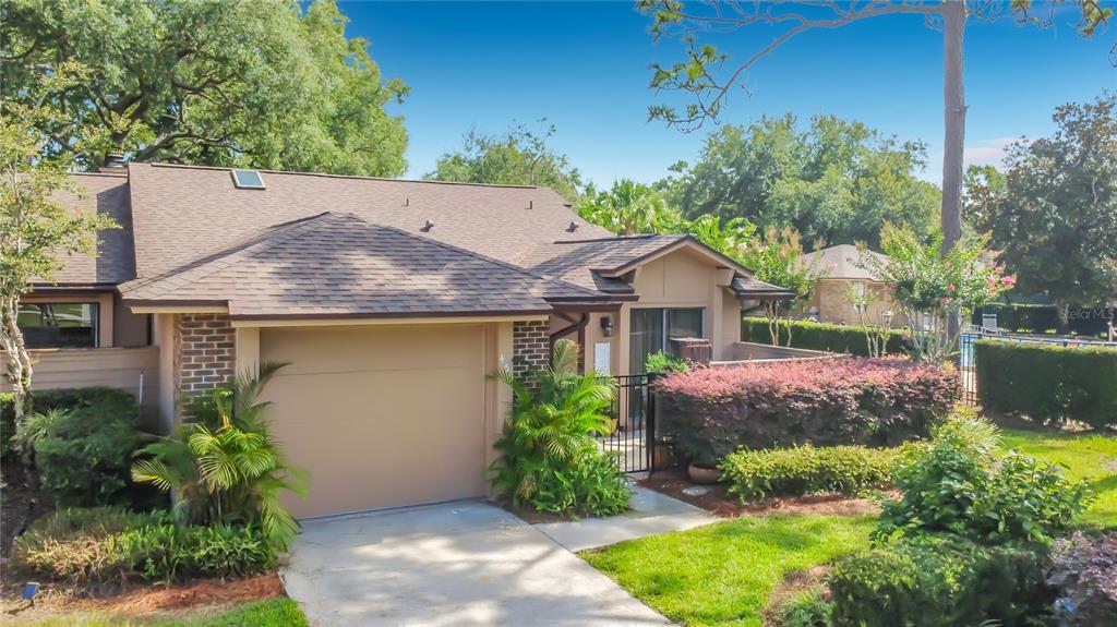A tan house exterior features a concrete patio with outdoor seating and a covered grill — 456 NEWTON PLACE, LONGWOOD, FL