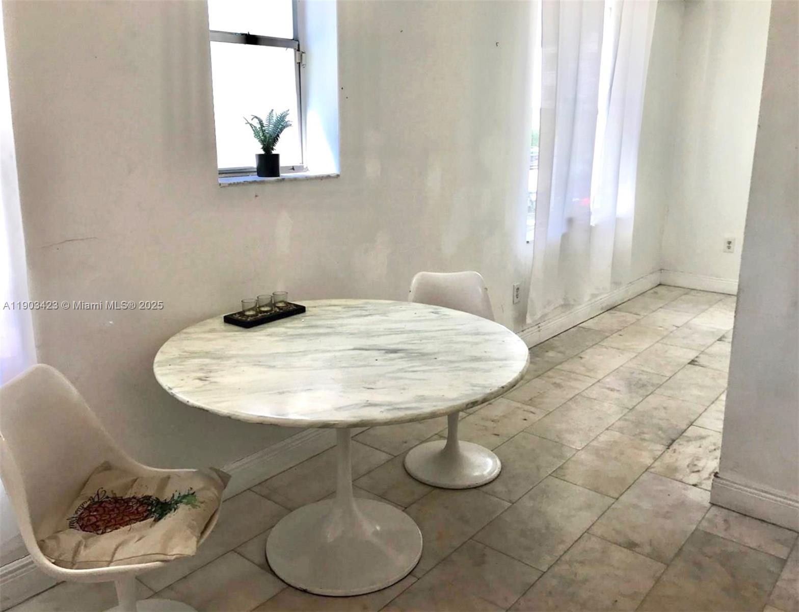 A round marble-topped pedestal table sits in a room with white walls and tiled floors — 1502 Jefferson Ave # 104, Miami Beach FL 33139, MIAMI BEACH, FL