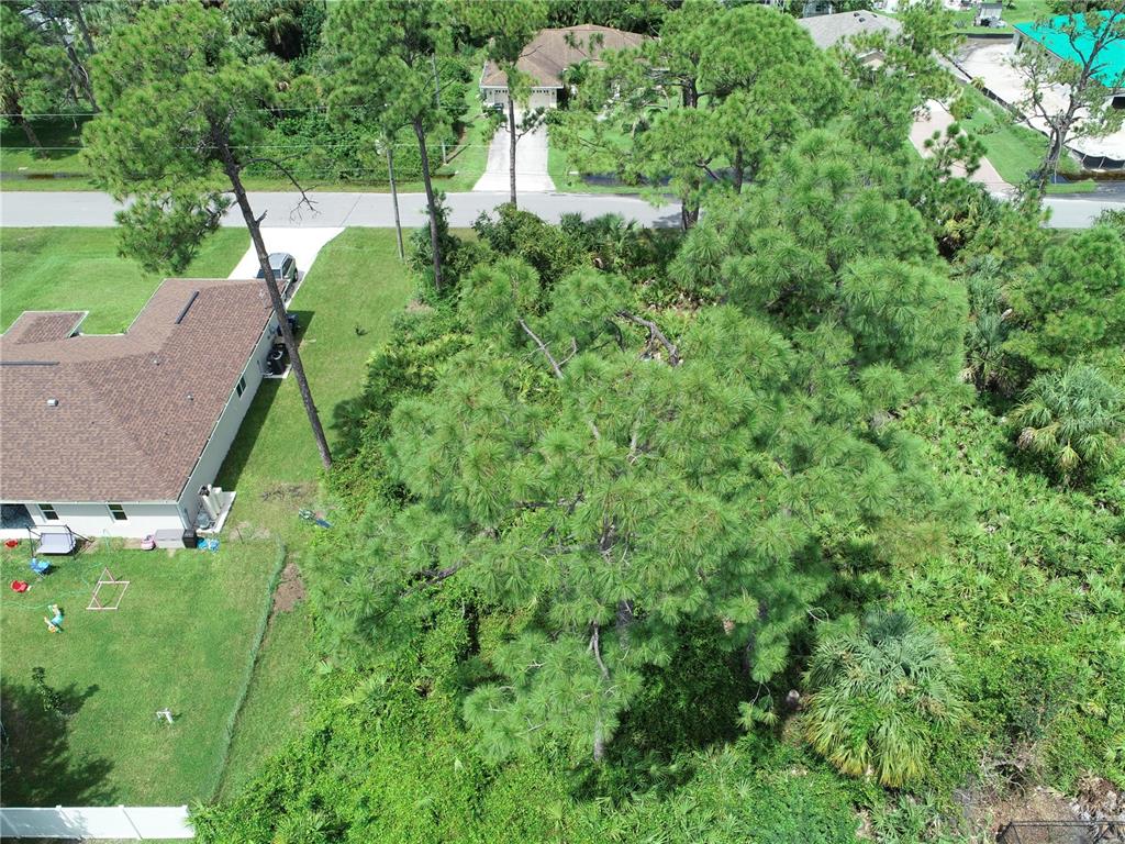 An aerial view shows a residential lot with a house, dense trees, and a paved road — Lot 38 ALLSUP TERRACE, NORTH PORT, FL