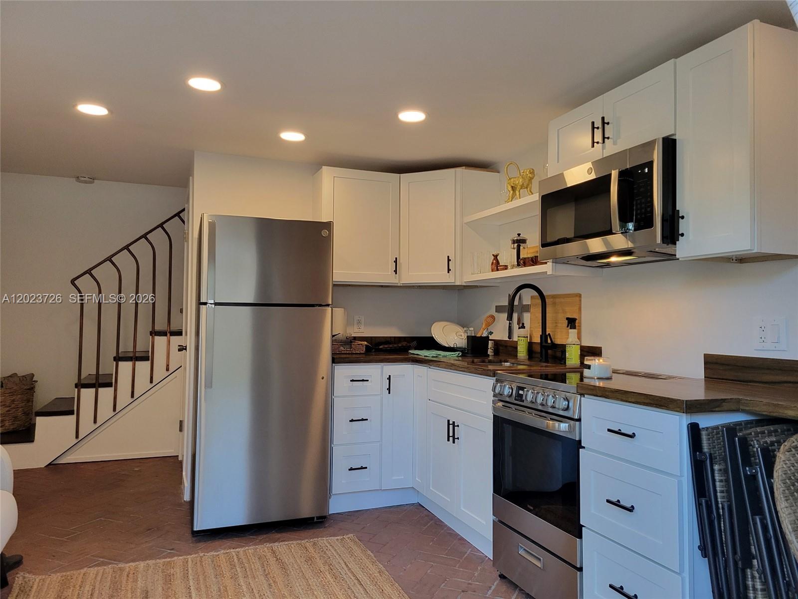 A kitchen features white cabinets, stainless steel appliances, and a dark wood countertop — 5866 SW 60th St # 3, Miami FL 33143, MIAMI, FL