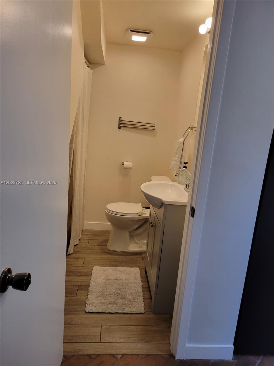 A small bathroom features a pedestal sink, a toilet, and wood-look flooring — 5866 SW 60th St # 3, Miami FL 33143, MIAMI, FL