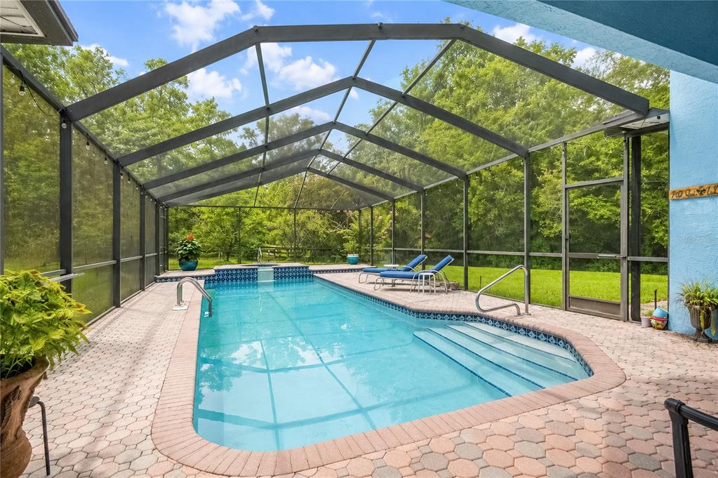 A rectangular swimming pool with a spa is enclosed by a screened lanai and patio — 20130 SW 95TH STREET, DUNNELLON, FL