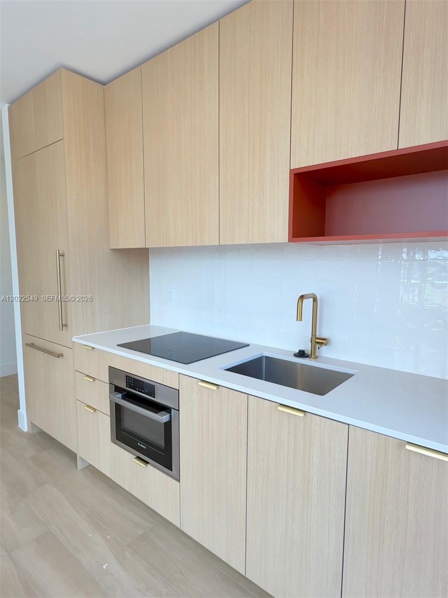 A modern kitchen features light wood cabinets, a red open shelf, and a white countertop — 90 NE 32nd ST # 201, Miami FL 33145, MIAMI, FL