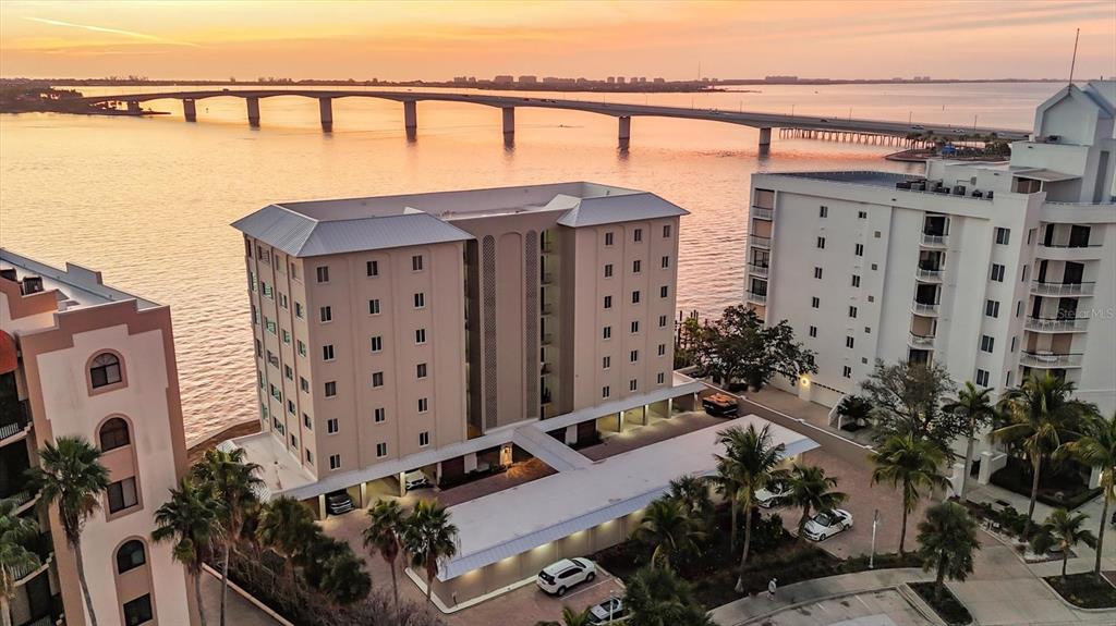 An aerial view shows a multi-story apartment building near a bridge over the water — 350 GOLDEN GATE POINT UNIT 62, SARASOTA, FL