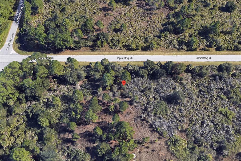 An aerial view shows a wooded, undeveloped lot located along a paved road — 263 SPAULDING STREET, PORT CHARLOTTE, FL