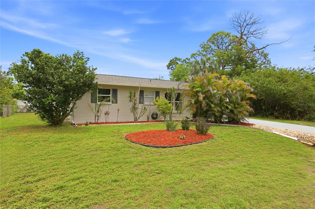 A single-story house with light-colored siding, a front lawn, and a red-mulched landscaping bed — 213 GRANADA BOULEVARD, NORTH PORT, FL