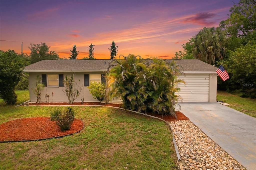 A single-story house with a gray exterior, a one-car garage, and a landscaped front yard — 213 GRANADA BOULEVARD, NORTH PORT, FL