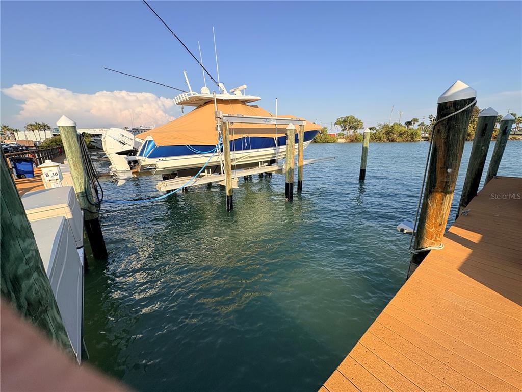 A boat on a mechanical lift is docked at a wooden pier over water — 601 AMERICAN LEGION DRIVE UNIT 16, ST PETERSBURG, FL