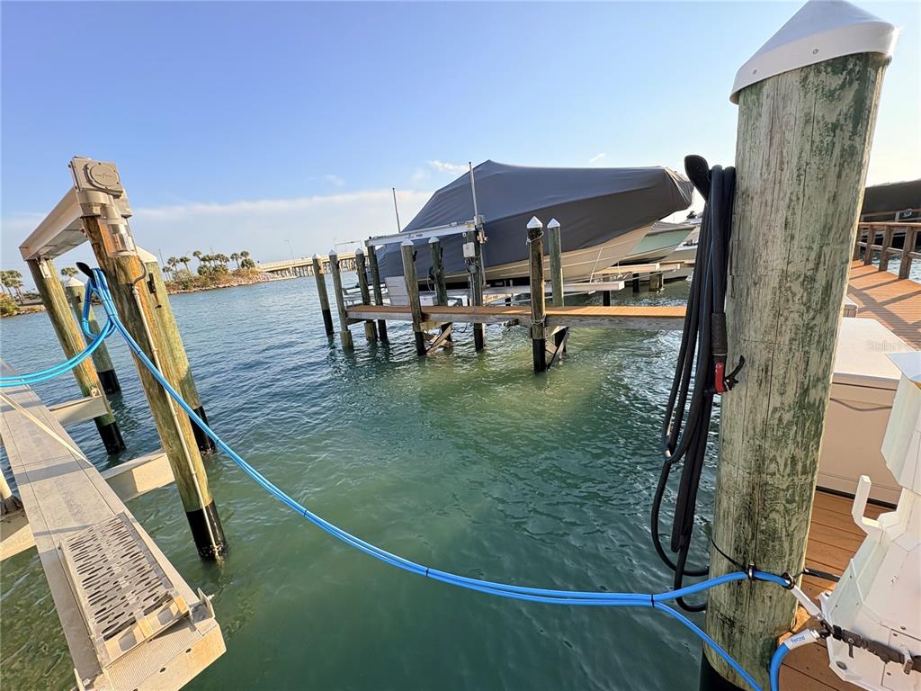 A boat covered by a gray tarp sits on a lift at a wooden dock — 601 AMERICAN LEGION DRIVE UNIT 16, ST PETERSBURG, FL