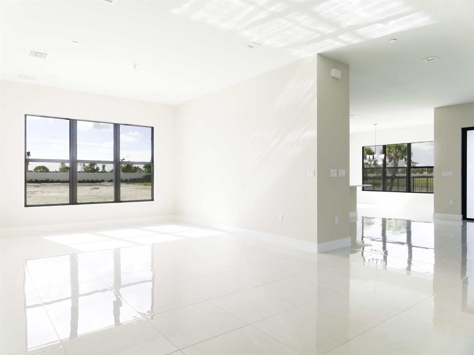 An empty room with white walls, glossy tile floors, and large windows overlooking a yard — 9895 Migration Point, Palm Beach Gardens FL 33412, PALM BEACH GARDENS, FL