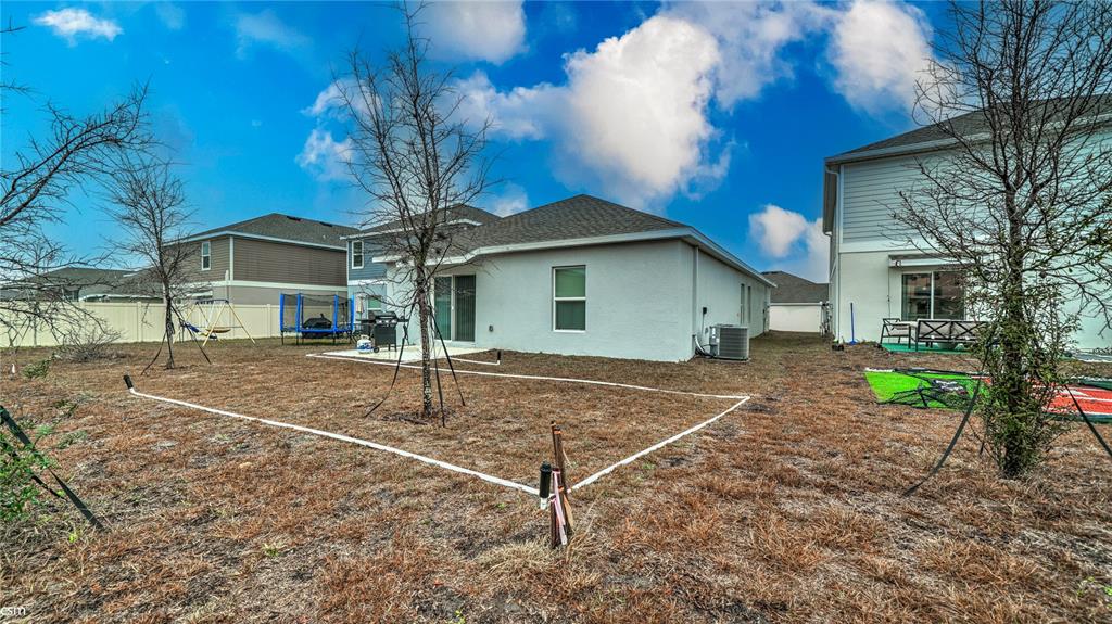 The backyard of a suburban house features a patio, a trampoline, and a marked area — 1760 WHITE WATER COURT, DAVENPORT, FL