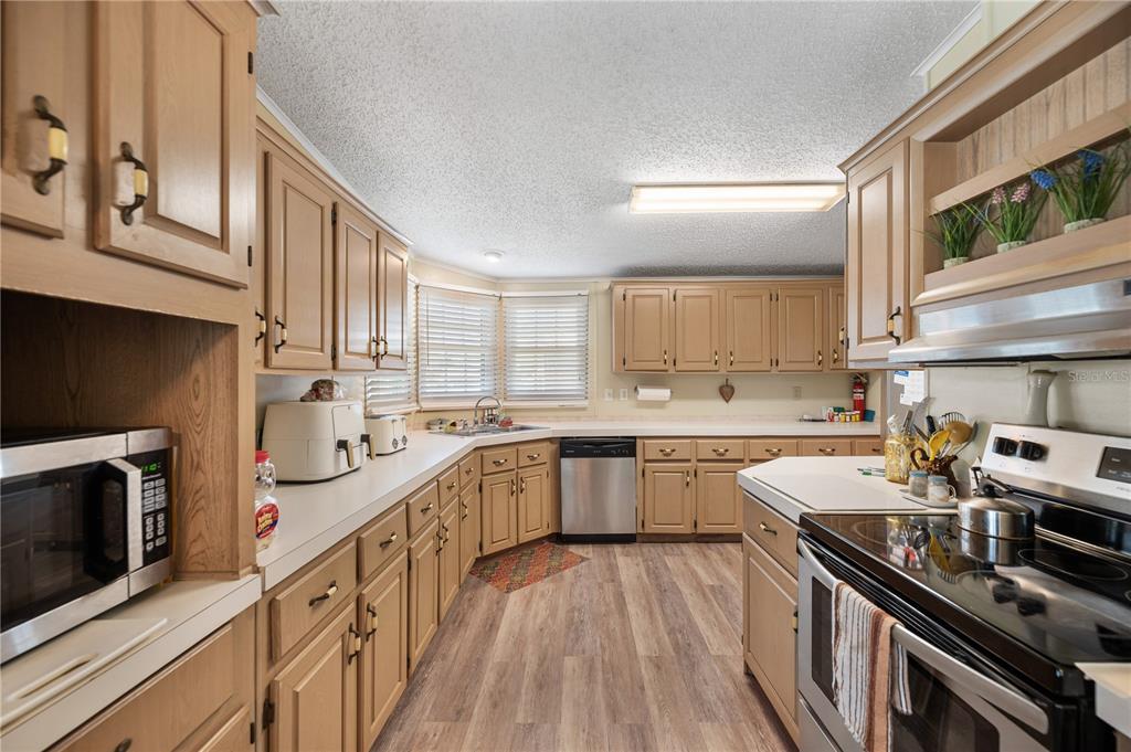 A kitchen with light wood cabinets, stainless steel appliances, and wood-look flooring — 1610 REYNOLDS ROAD UNIT 333, LAKELAND, FL